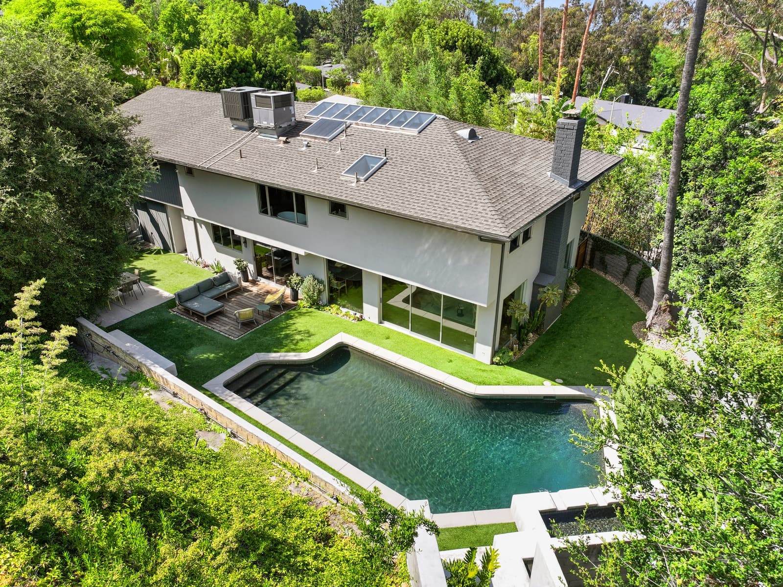 Aerial view of a two-story LA home with a lush garden and pool
