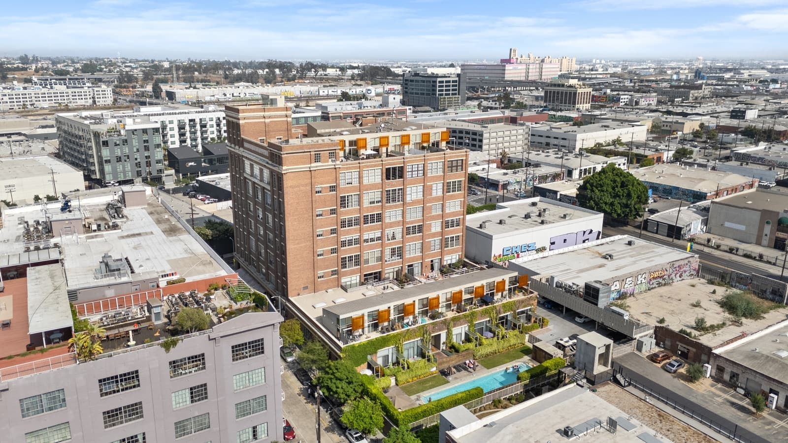 Drone over a brick loft building and its rooftop pool, Arts District
