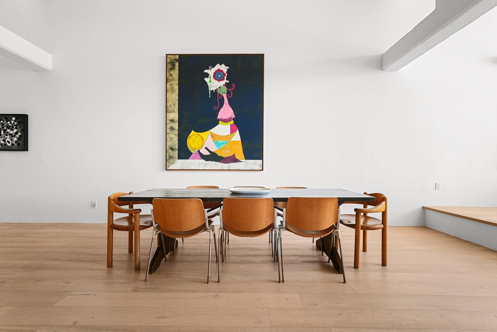 Loft dining table under a large portrait, seen straight on