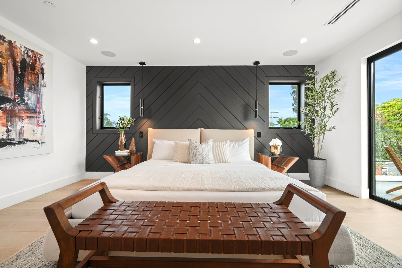 A bedroom with a black herringbone wall and a leather bench.