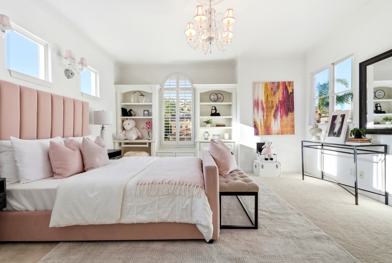 Bedroom with a blush headboard and a crystal chandelier