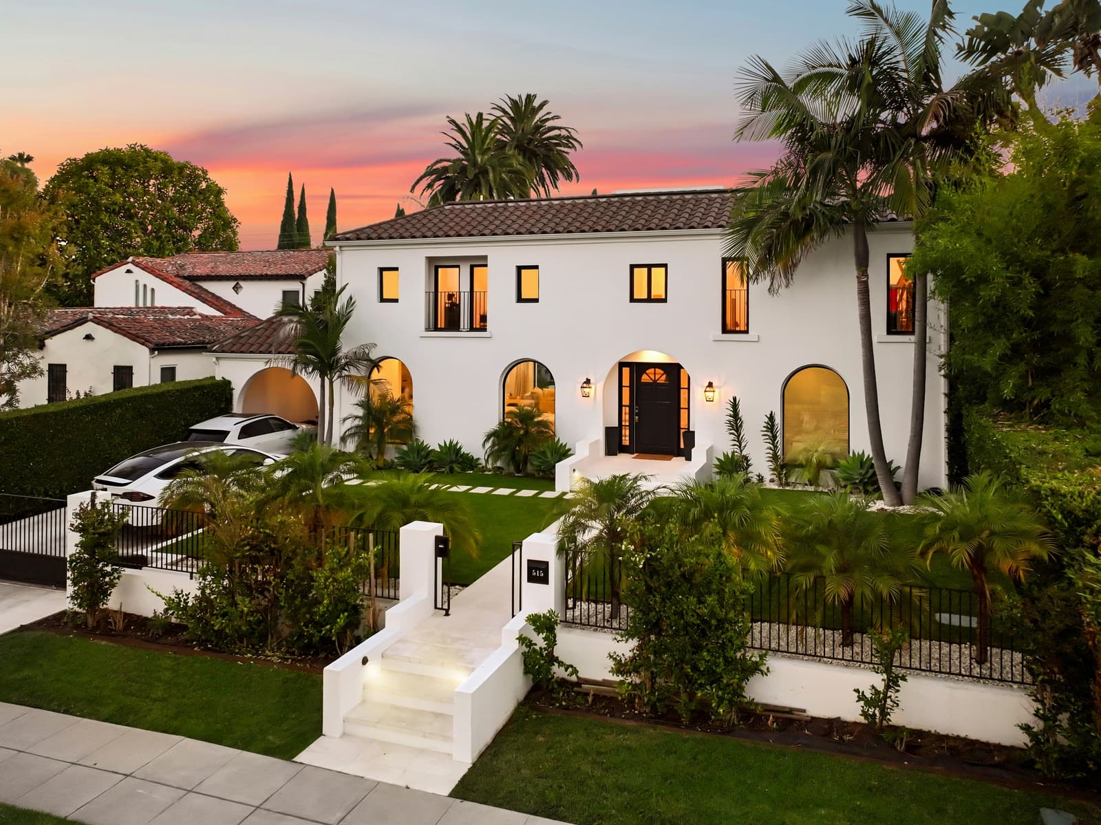Drone over a Beverly Hills home from the street, palms in a row