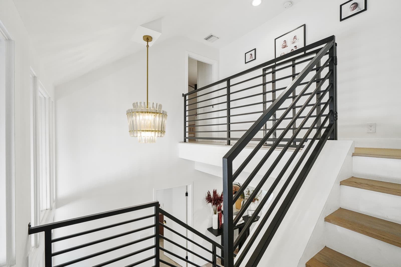 Black steel stair rail under a glass chandelier