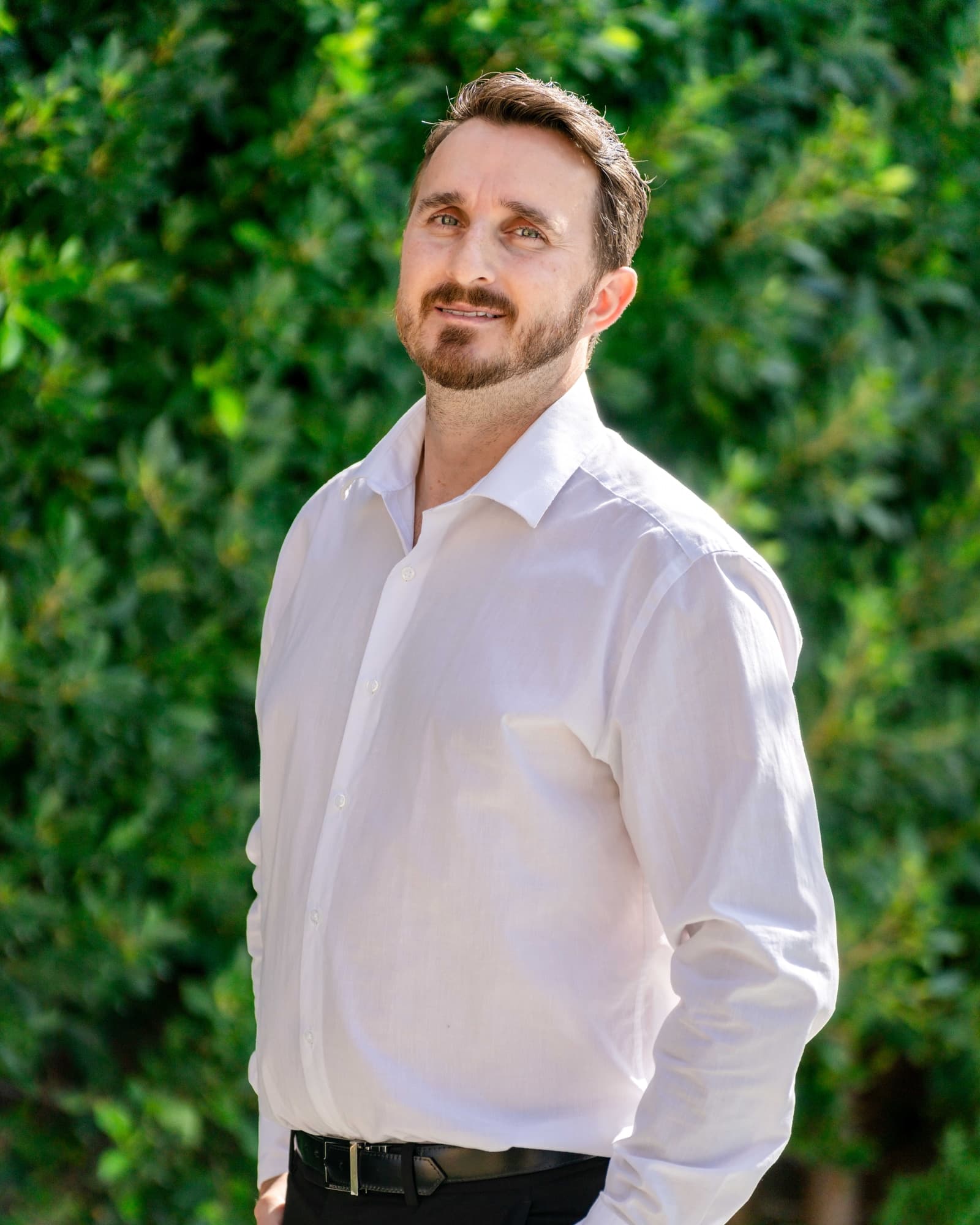 Agent portrait against a green hedge