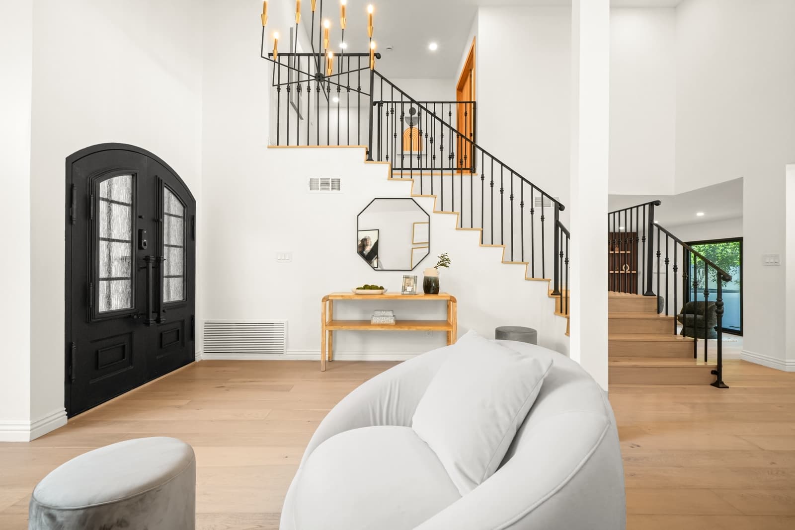 Arched black front door, open stair and living room beyond
