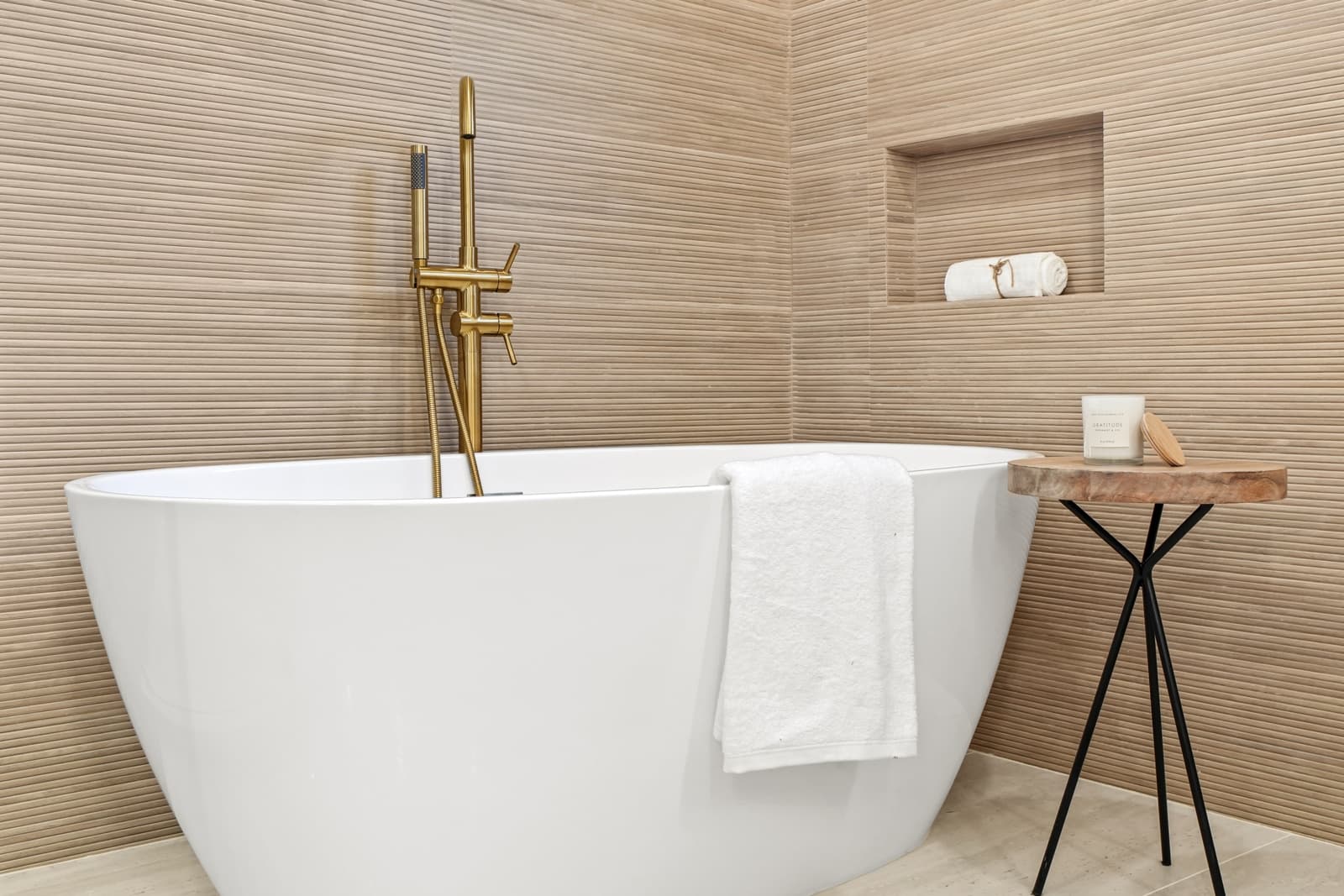 Freestanding tub against a limestone-tiled wall