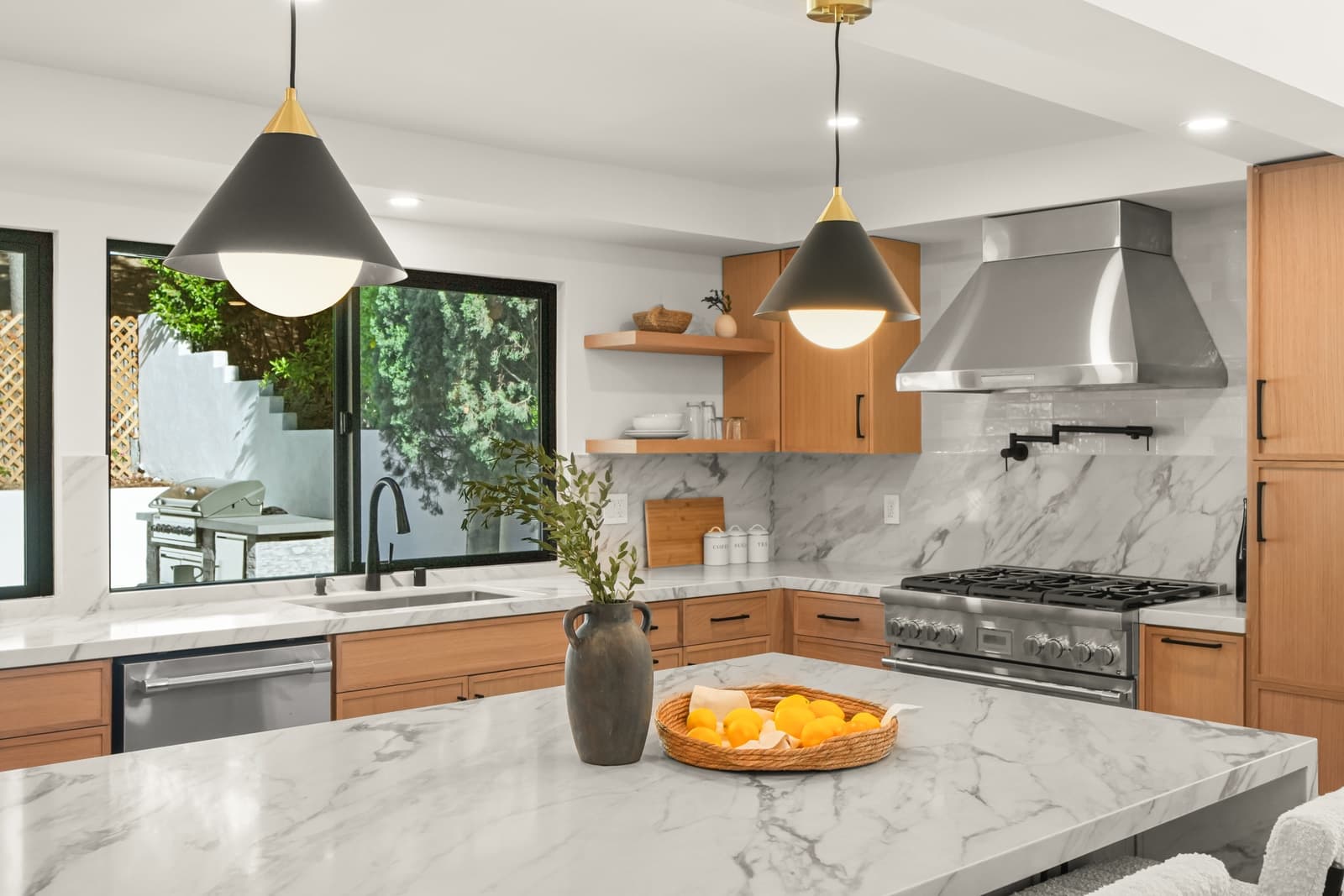 Oak kitchen with a marble island and brass pendants