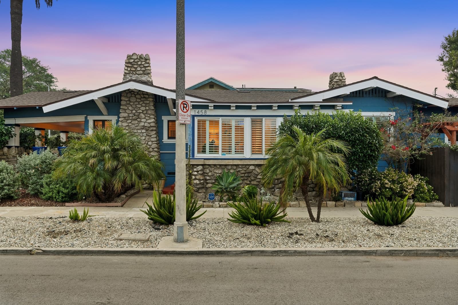Craftsman bungalow at twilight, river-rock porch piers and a pink sky