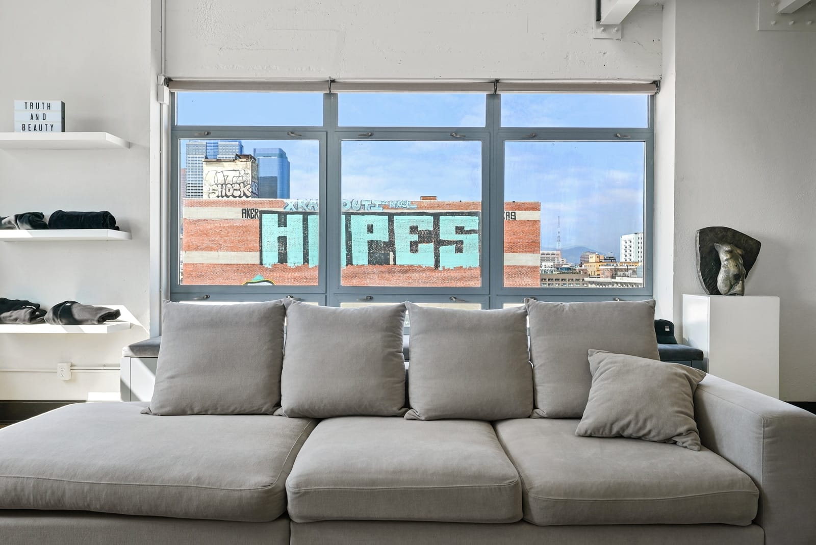 Loft sofa facing a window full of a painted brick mural