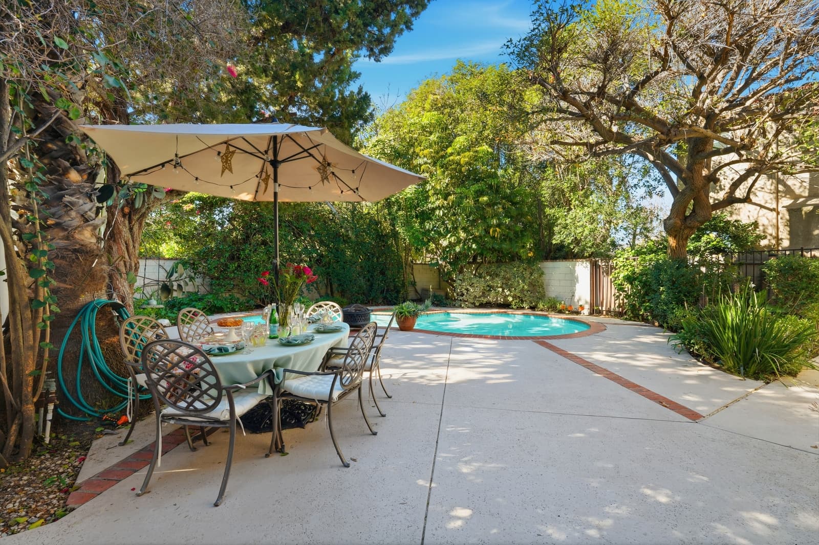 Backyard pool and patio framed by mature landscaping