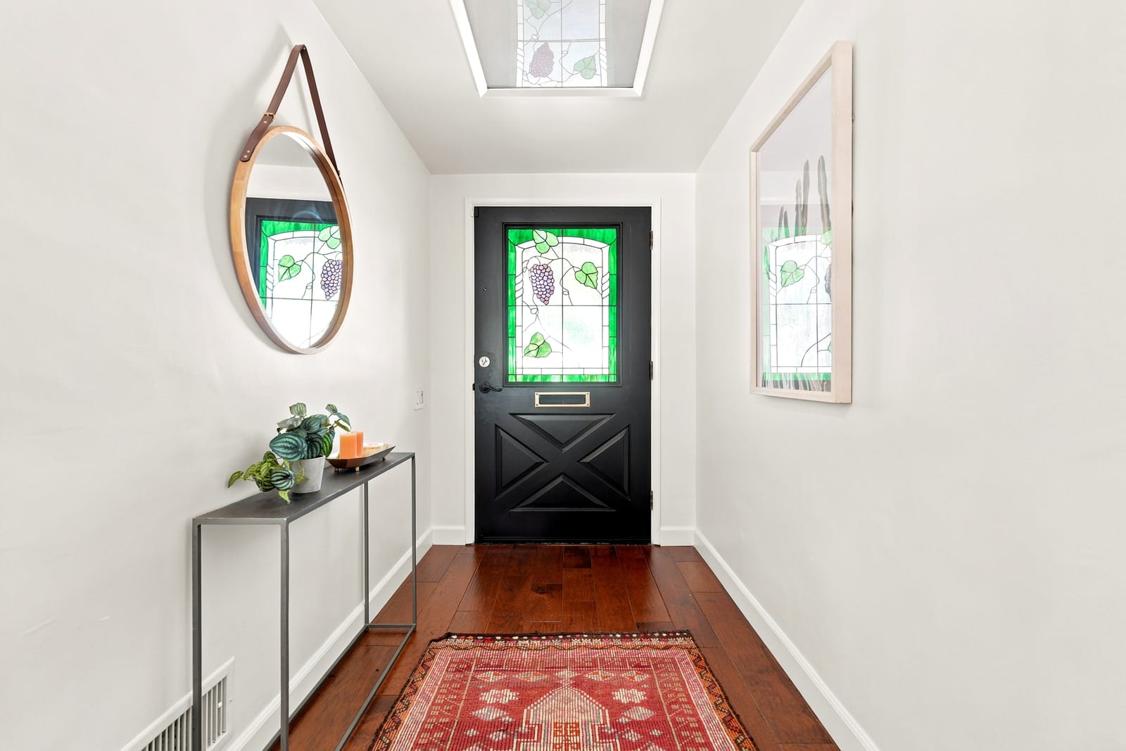 Entry with a black stained-glass door and a red runner