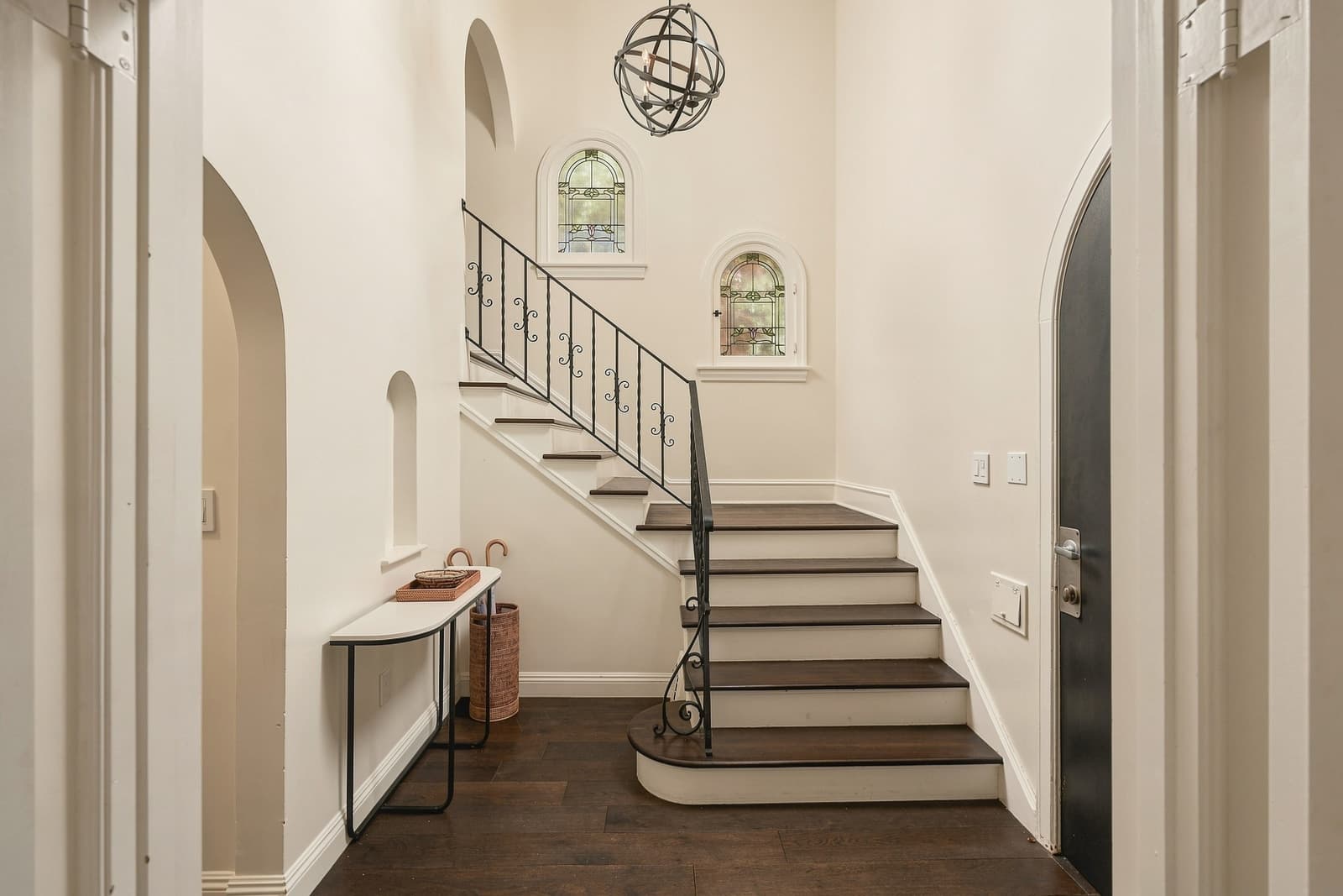 Entry with an iron-railed staircase and arched doorways
