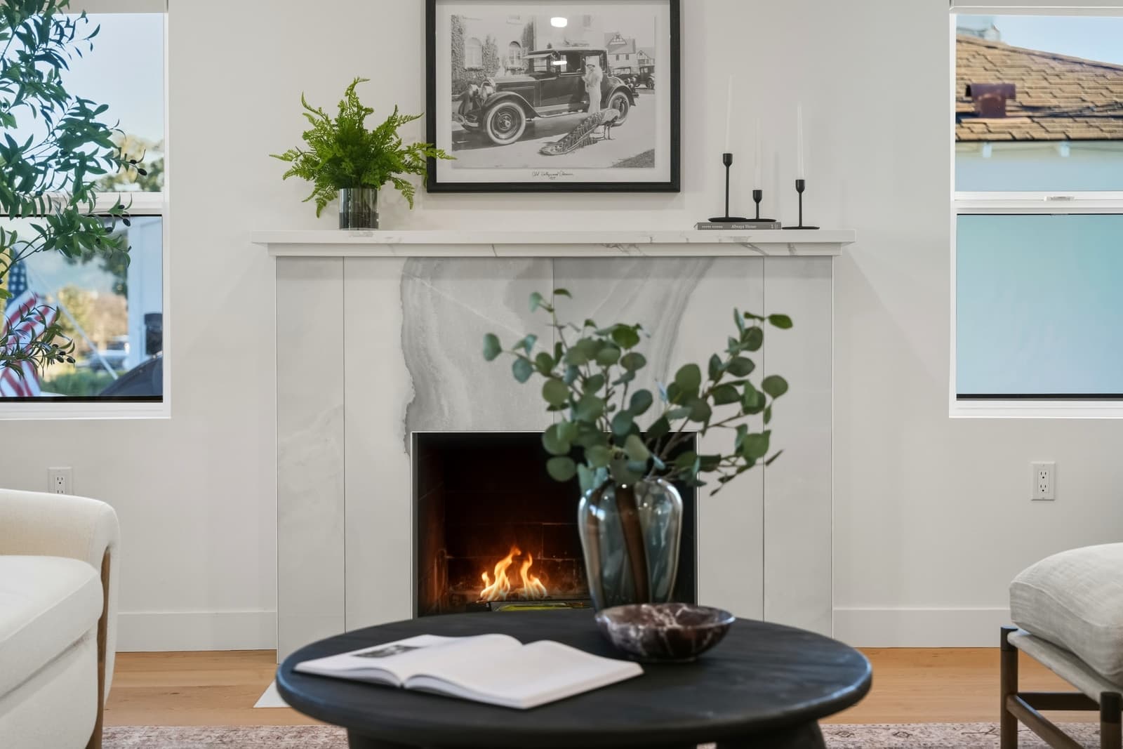 Living room with the fireplace lit, a fern on the mantel and eucalyptus on the coffee table