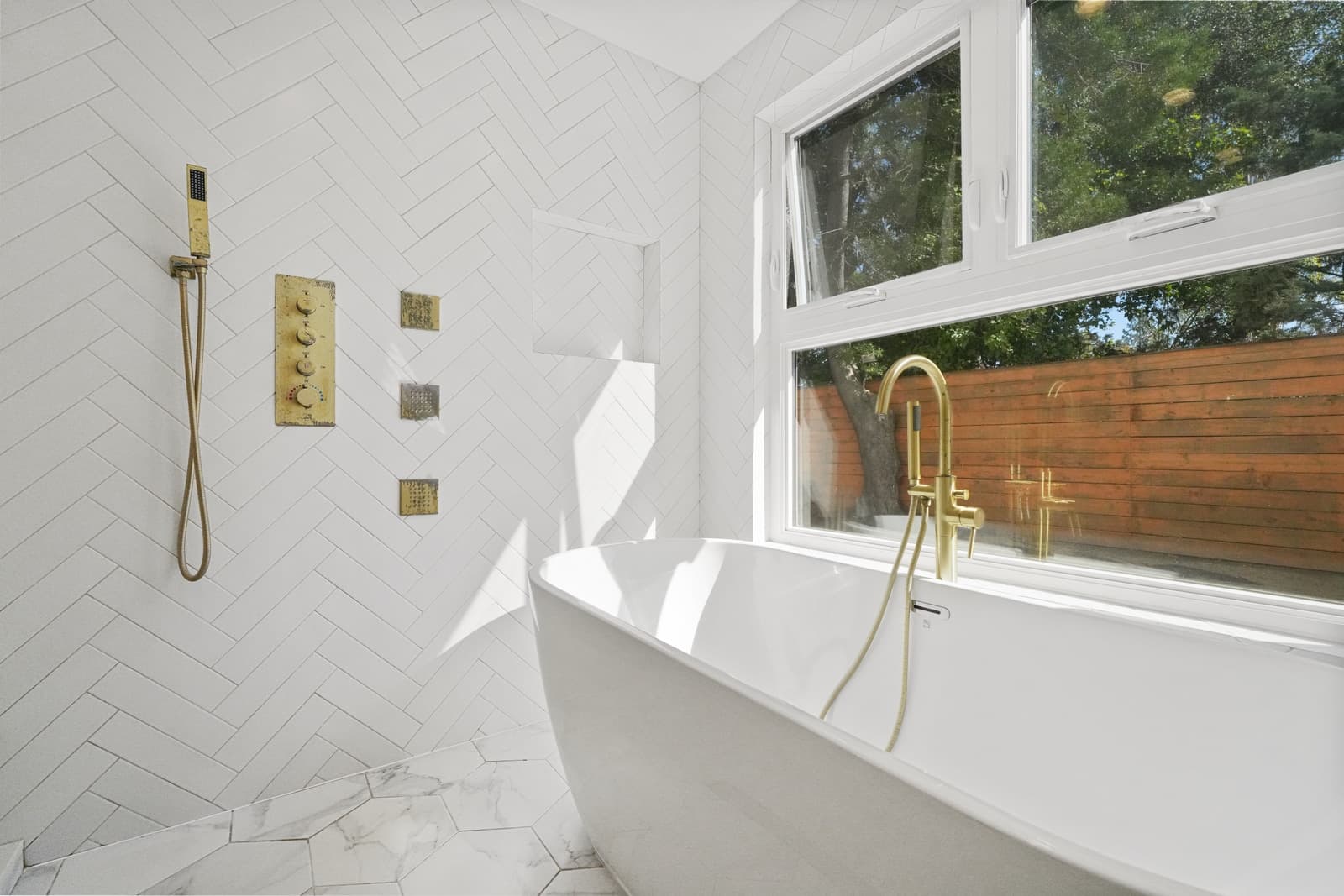 Freestanding tub with a brass filler, cedar fence outside