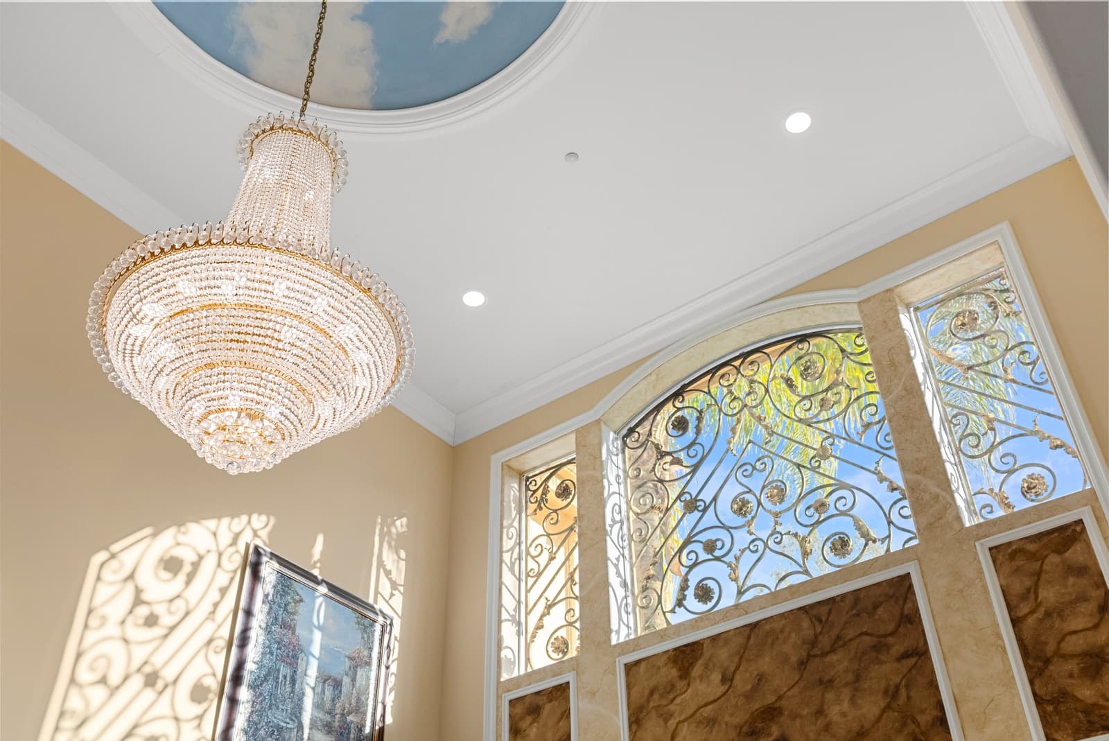 Entry with a crystal chandelier and ornate iron doors