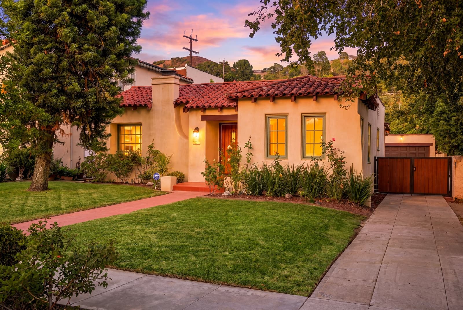 Glendale Spanish bungalow at twilight under a tree, windows lit