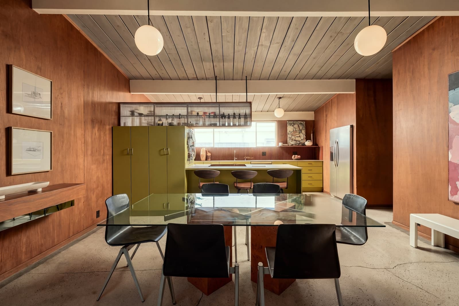 Dining room looking through to a yellow kitchen under a wood ceiling