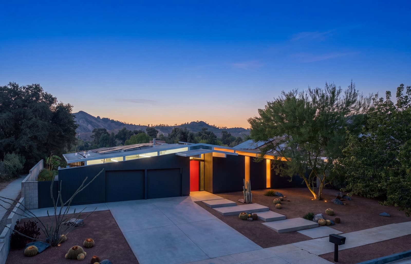 Low midcentury home at twilight, mountains behind and the entry glowing