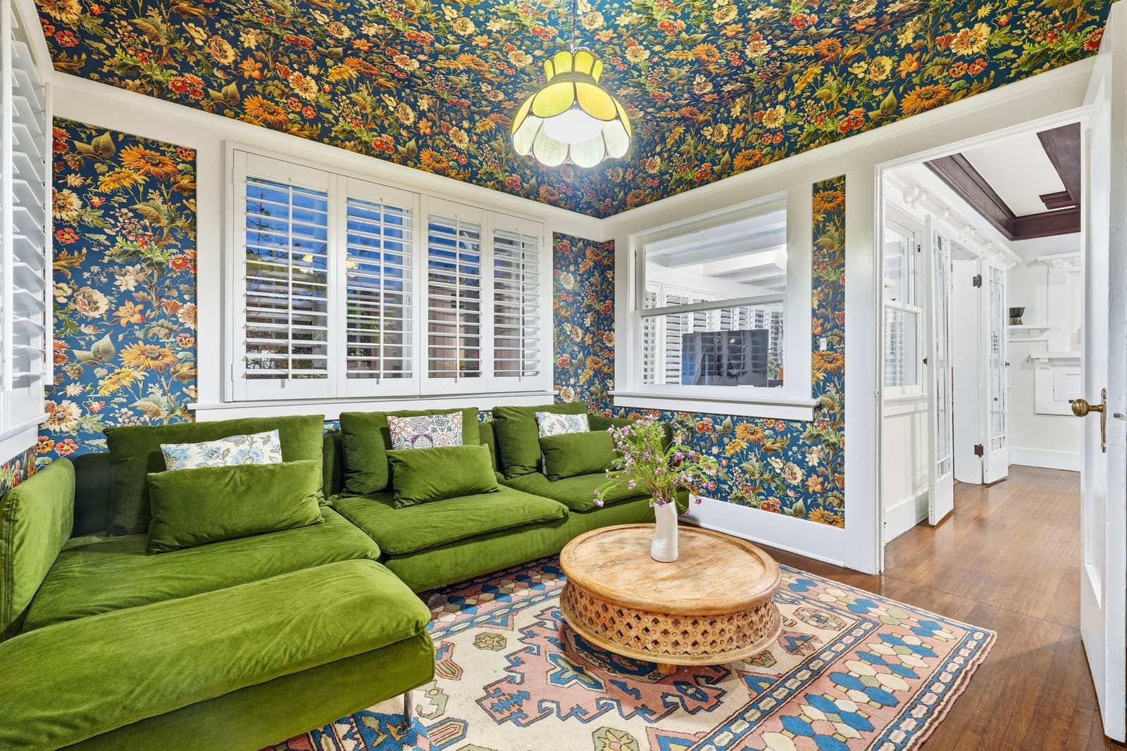 A green velvet sectional against botanical wallpaper.