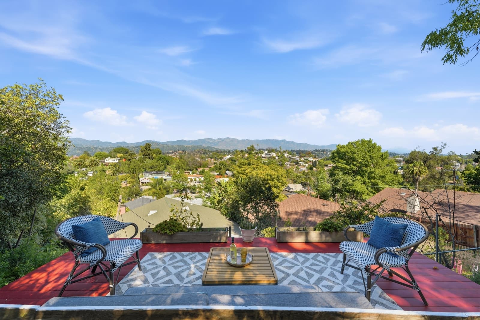 Red deck with black rattan chairs and a hill view, Highland Park