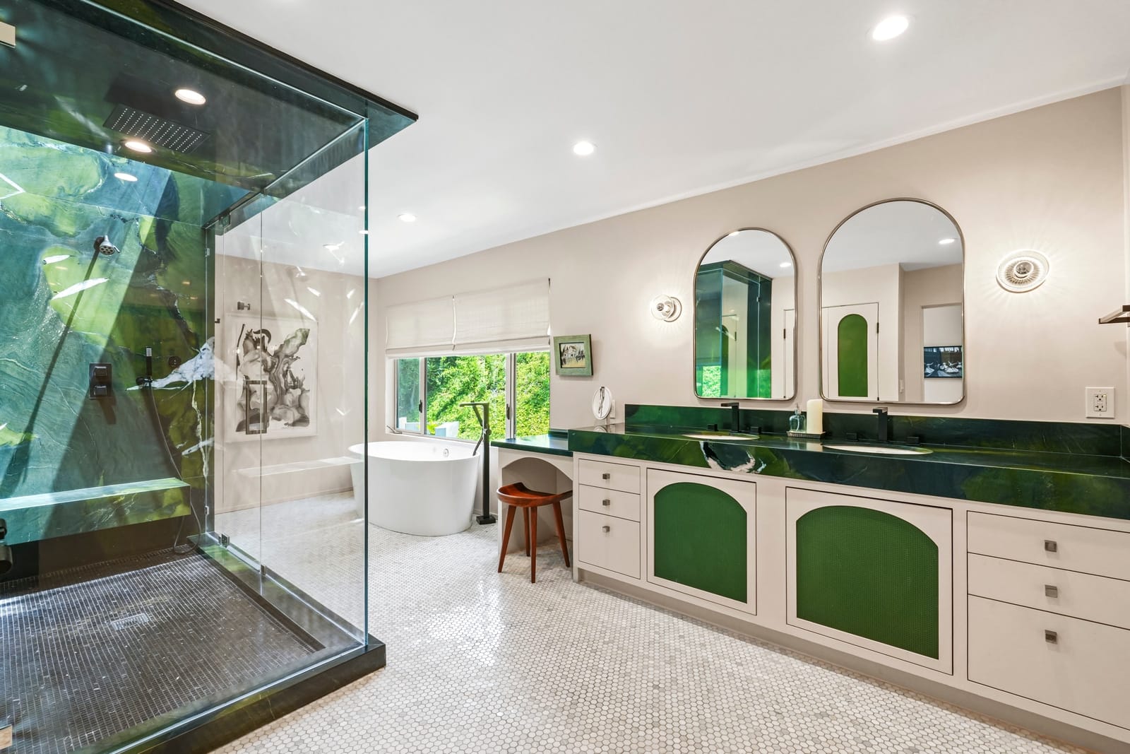 Primary bath with a glass shower enclosure and green arched vanities