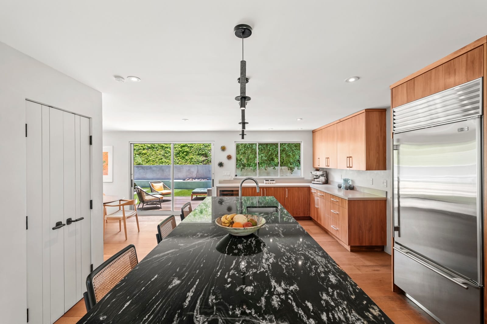Walnut kitchen with a long black marble island under pendant lights