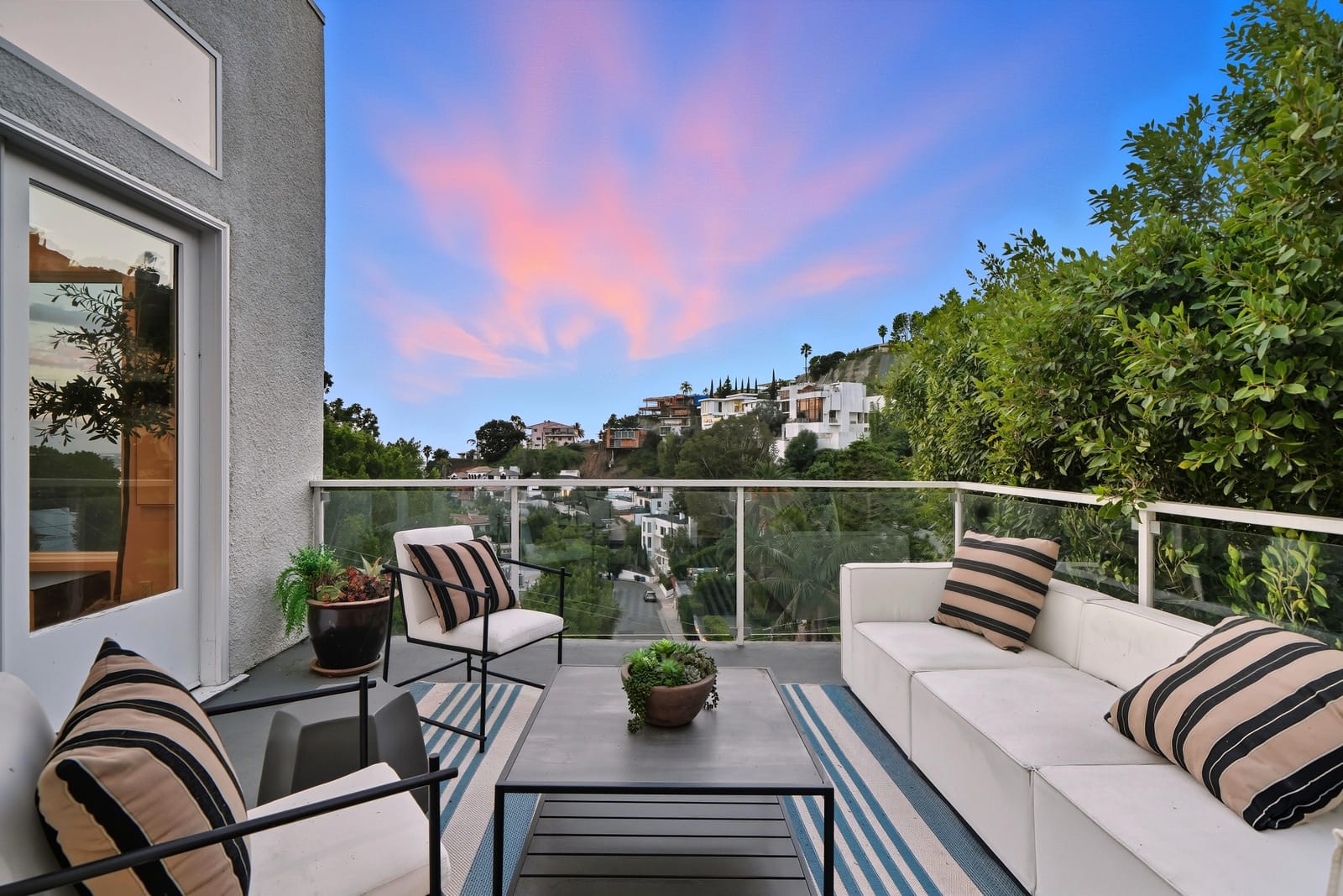 Balcony lounge under a pink sunset over the hills