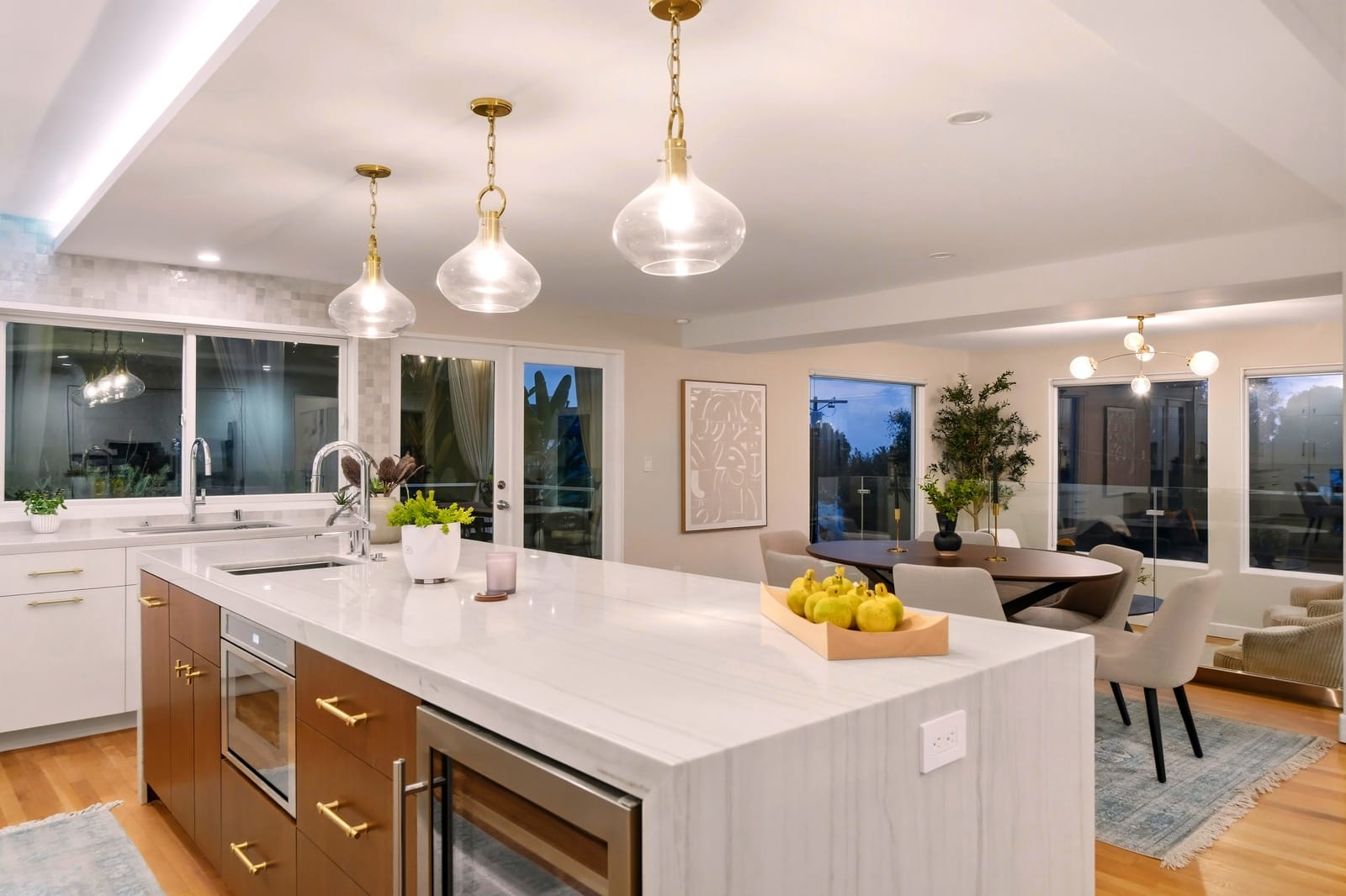 Kitchen island under glass pendants, dining beyond