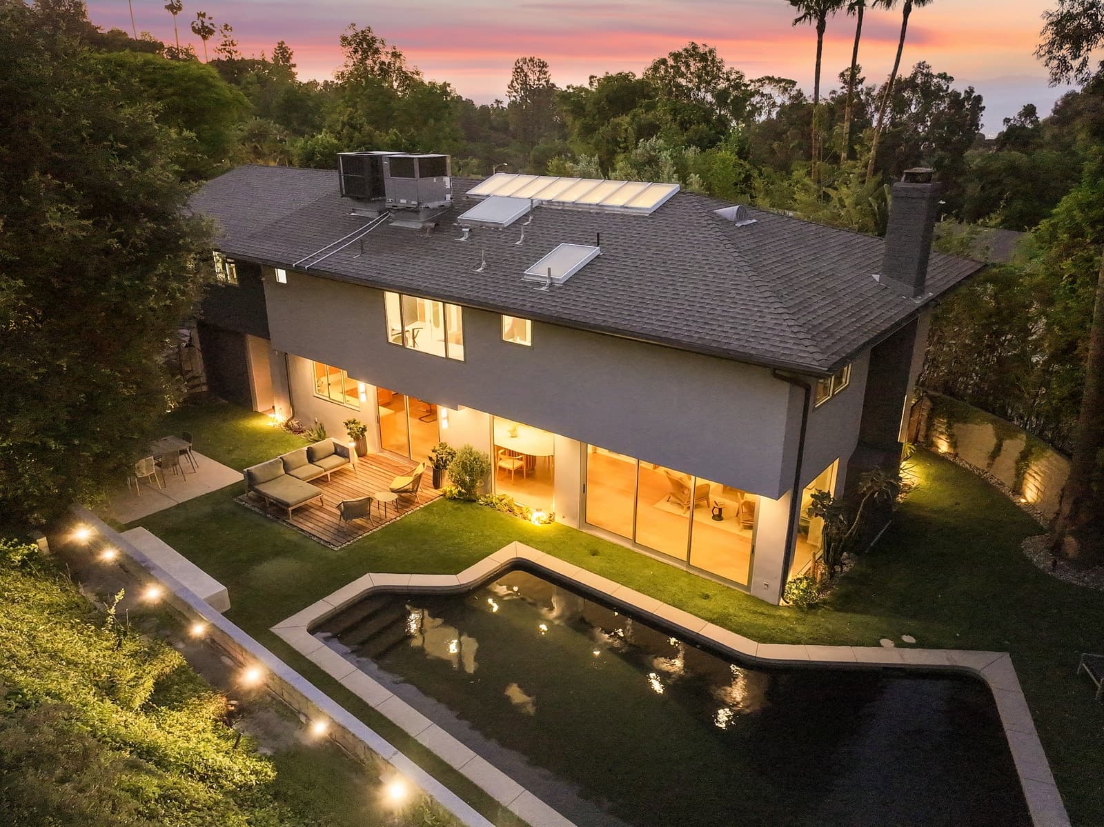 Drone twilight over a Hollywood Hills modern, pool lit below