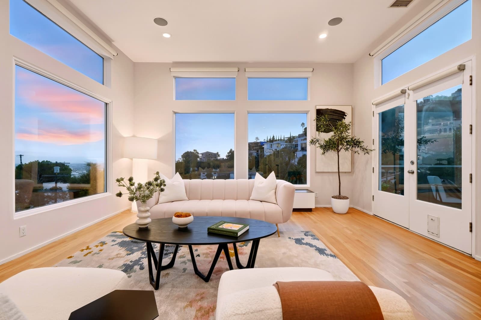 Living room at twilight with the city through floor-to-ceiling windows