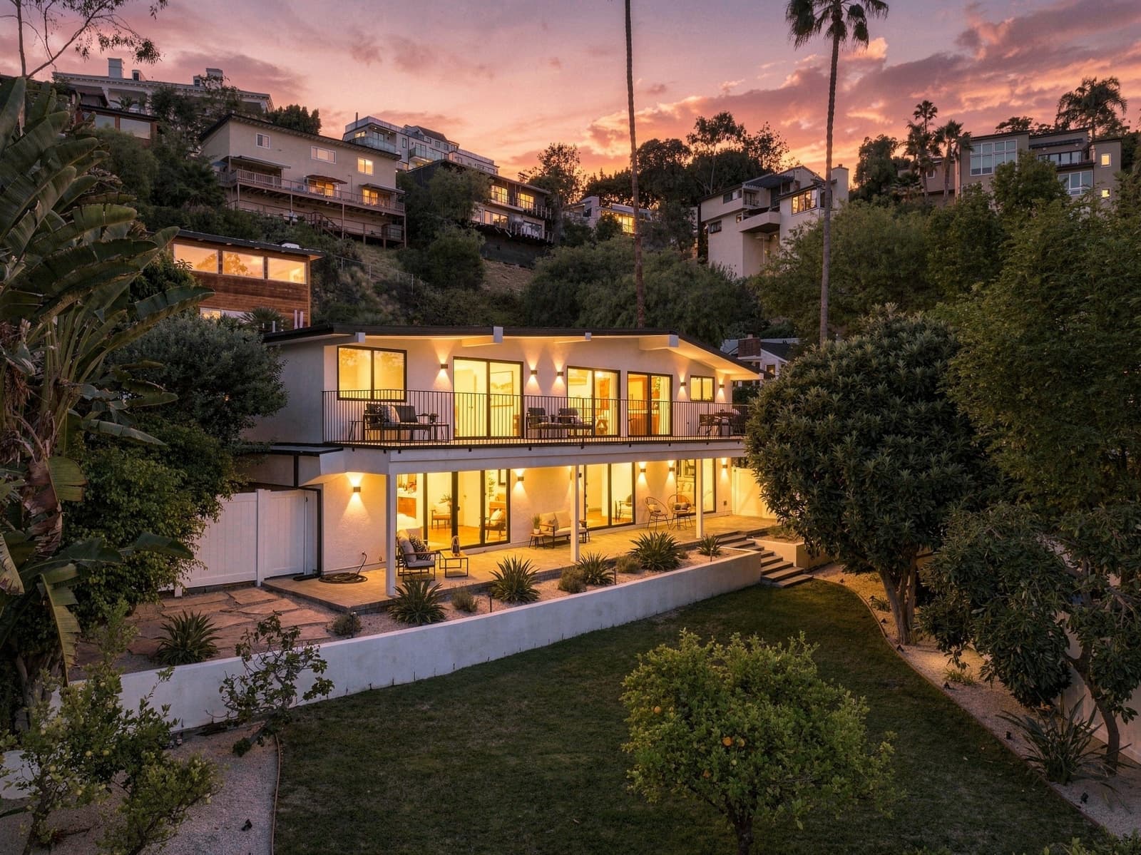 Mid-century modern at twilight, every room lit against the Hollywood Hills