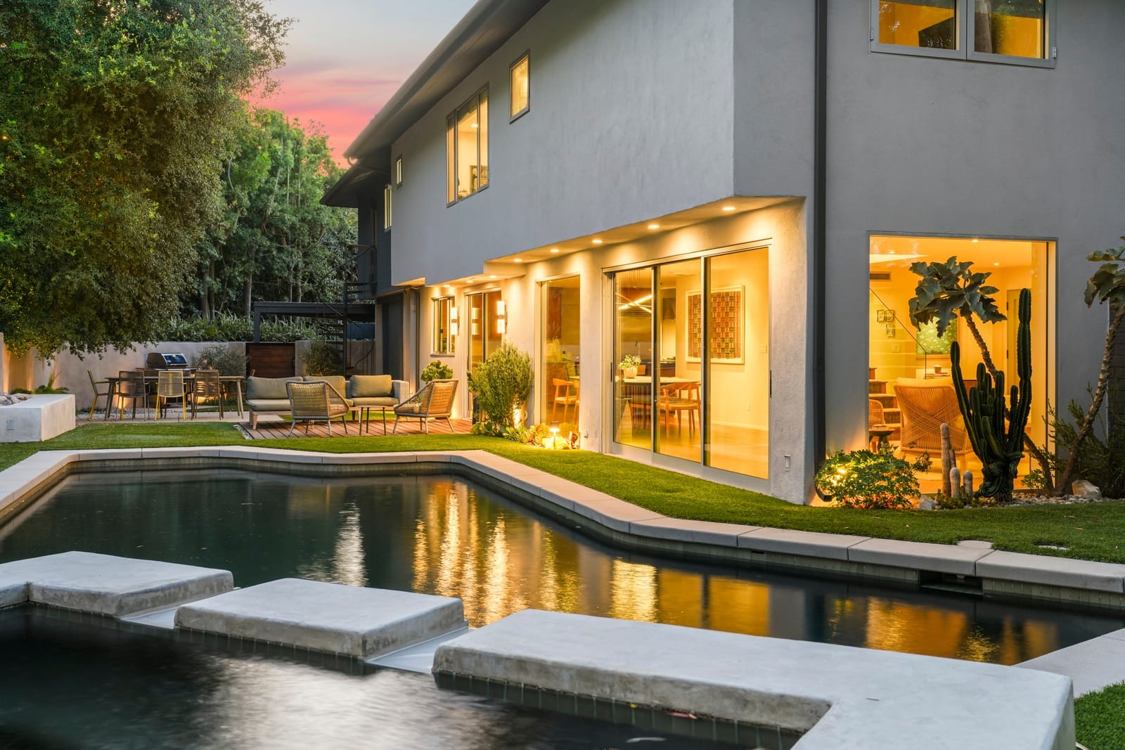 Pool with stepping pads at twilight, the house lit behind
