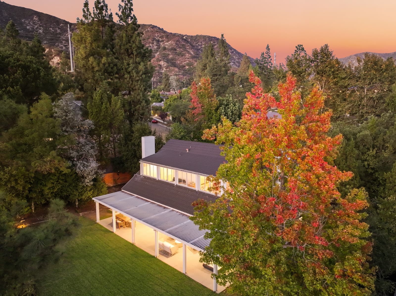 Drone over a modern farmhouse in autumn color, mountains behind