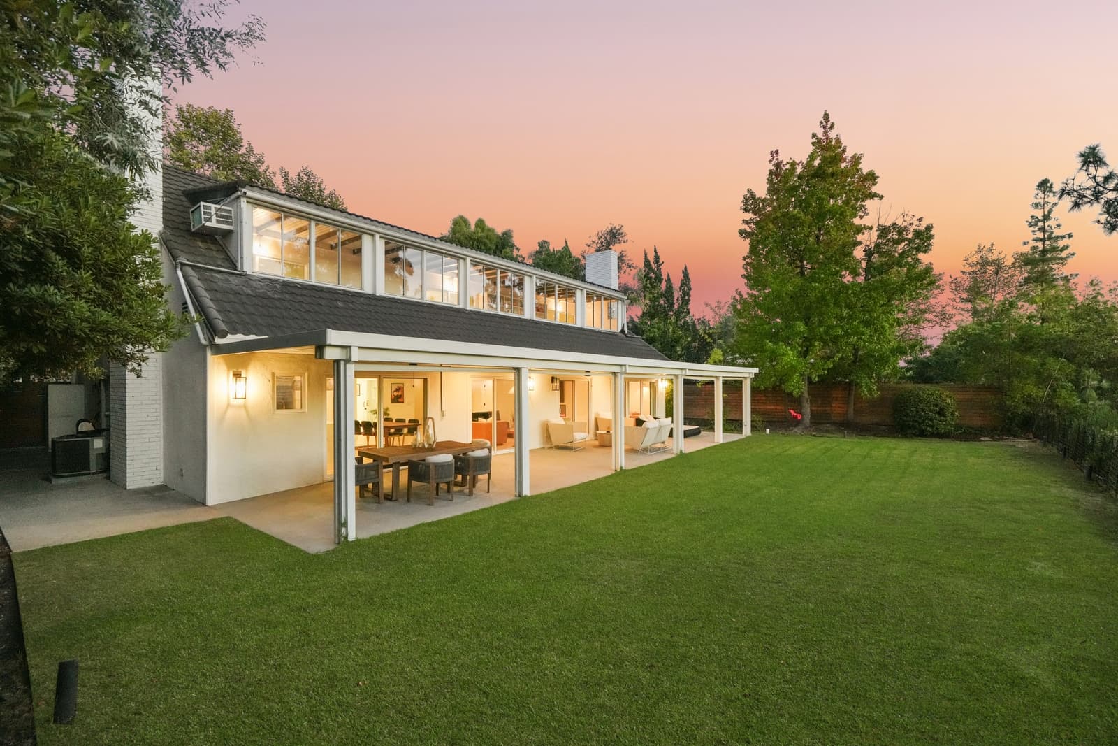 La Cañada modern farmhouse at twilight across the lawn, pink sky