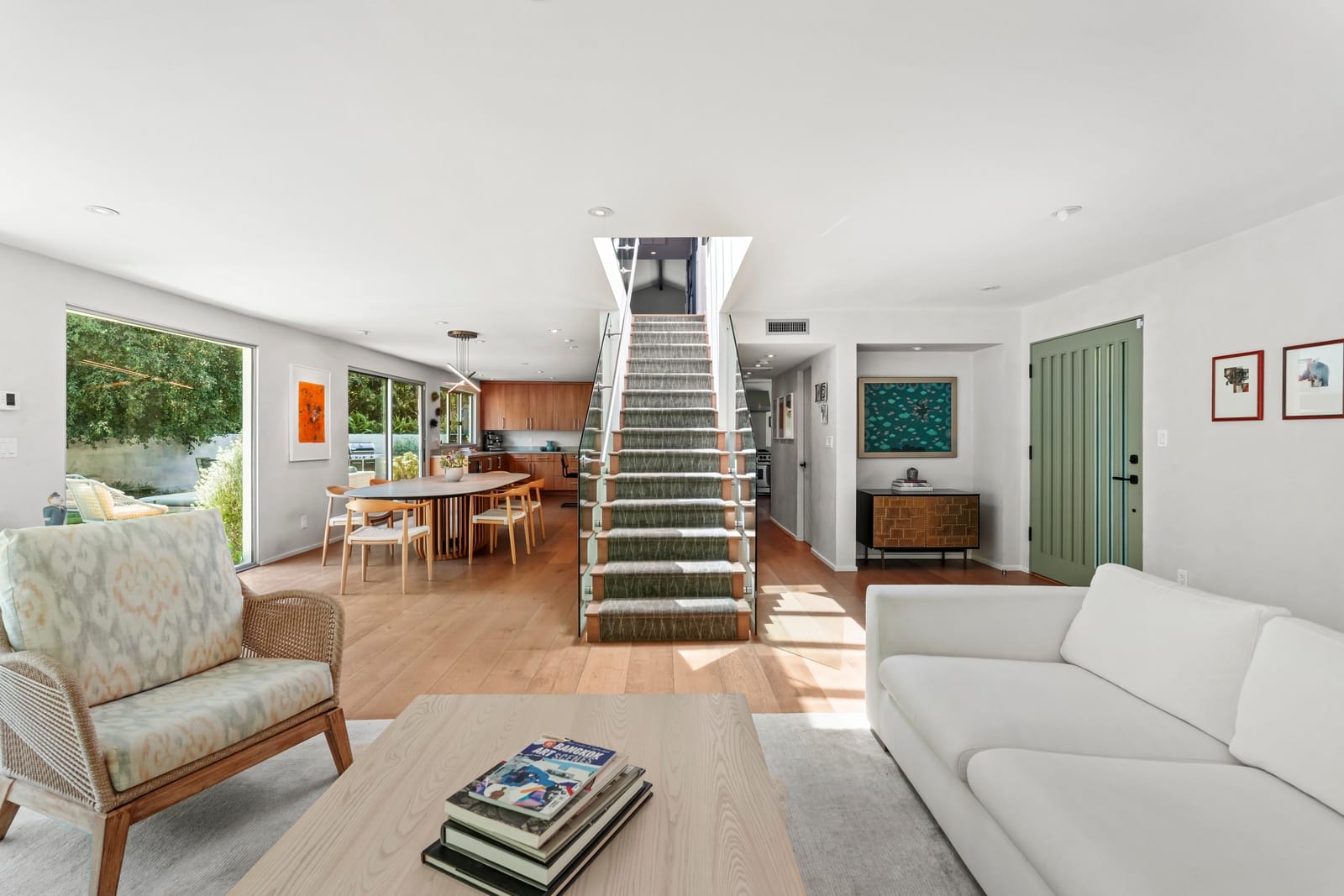 Living room with an open stair, white sofa and a dining table beyond