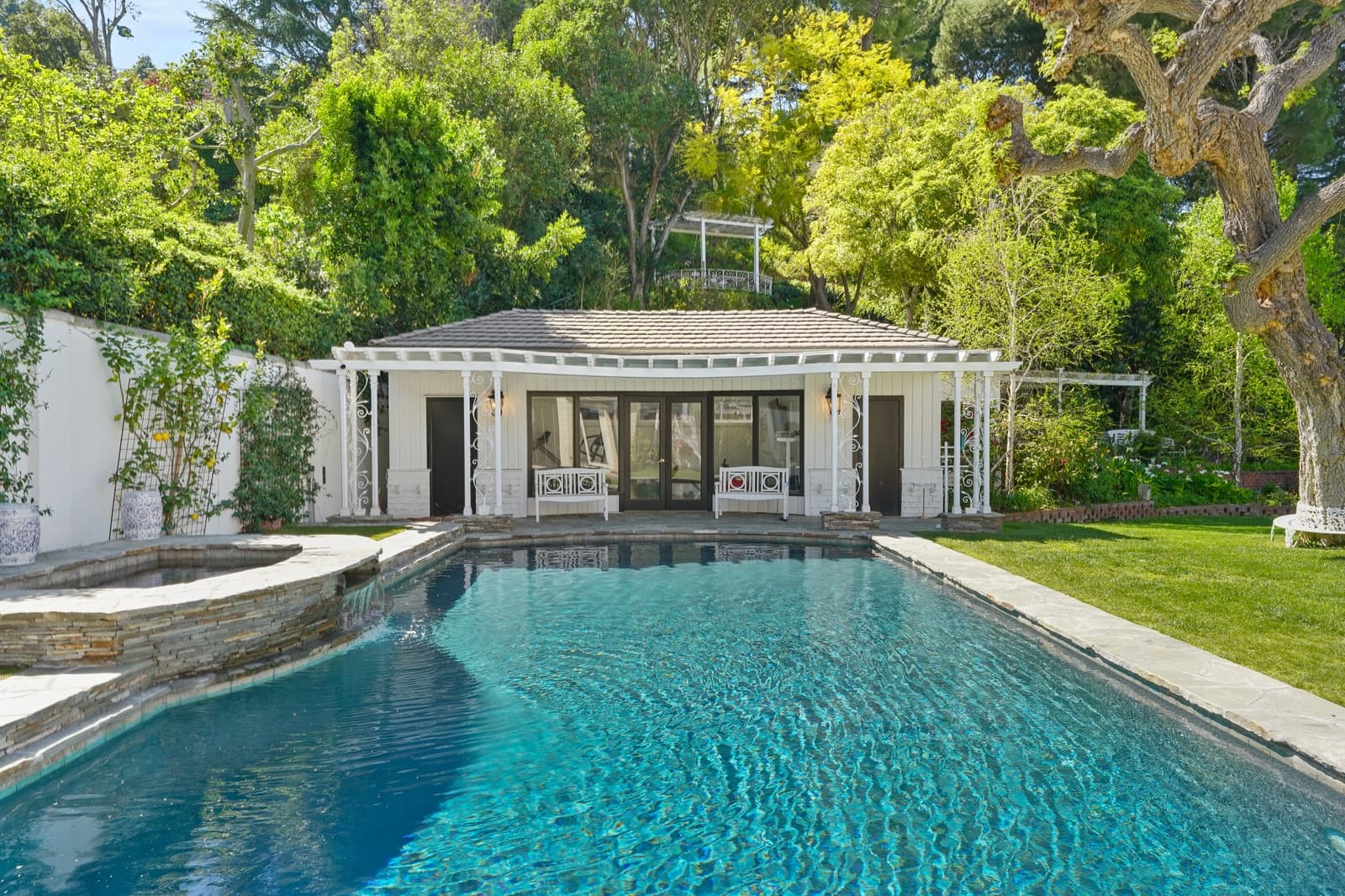 White pool house with columns at the end of the pool