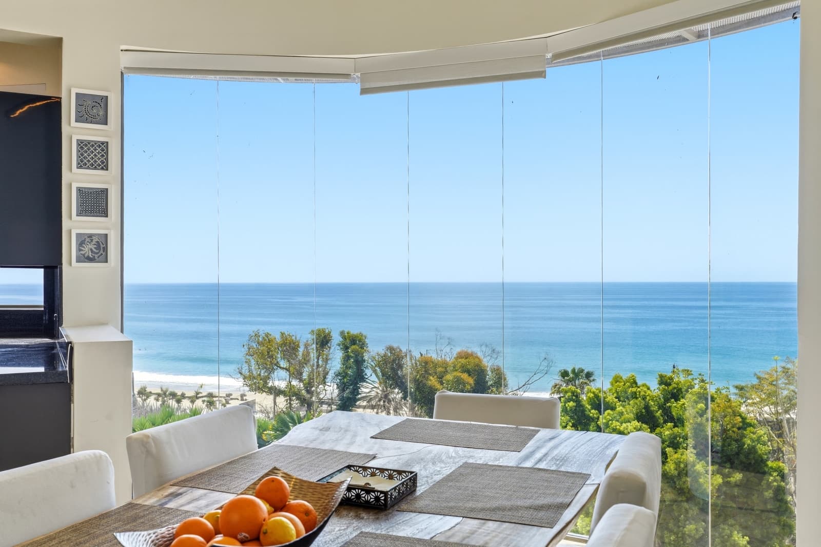 Dining table behind curved glass, the Pacific filling the view