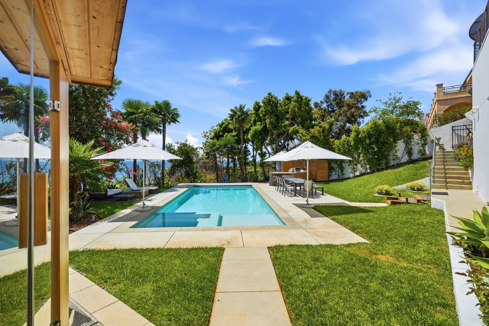 Pool terrace with palm trees and an ocean glimpse, photographed by VVT in Malibu