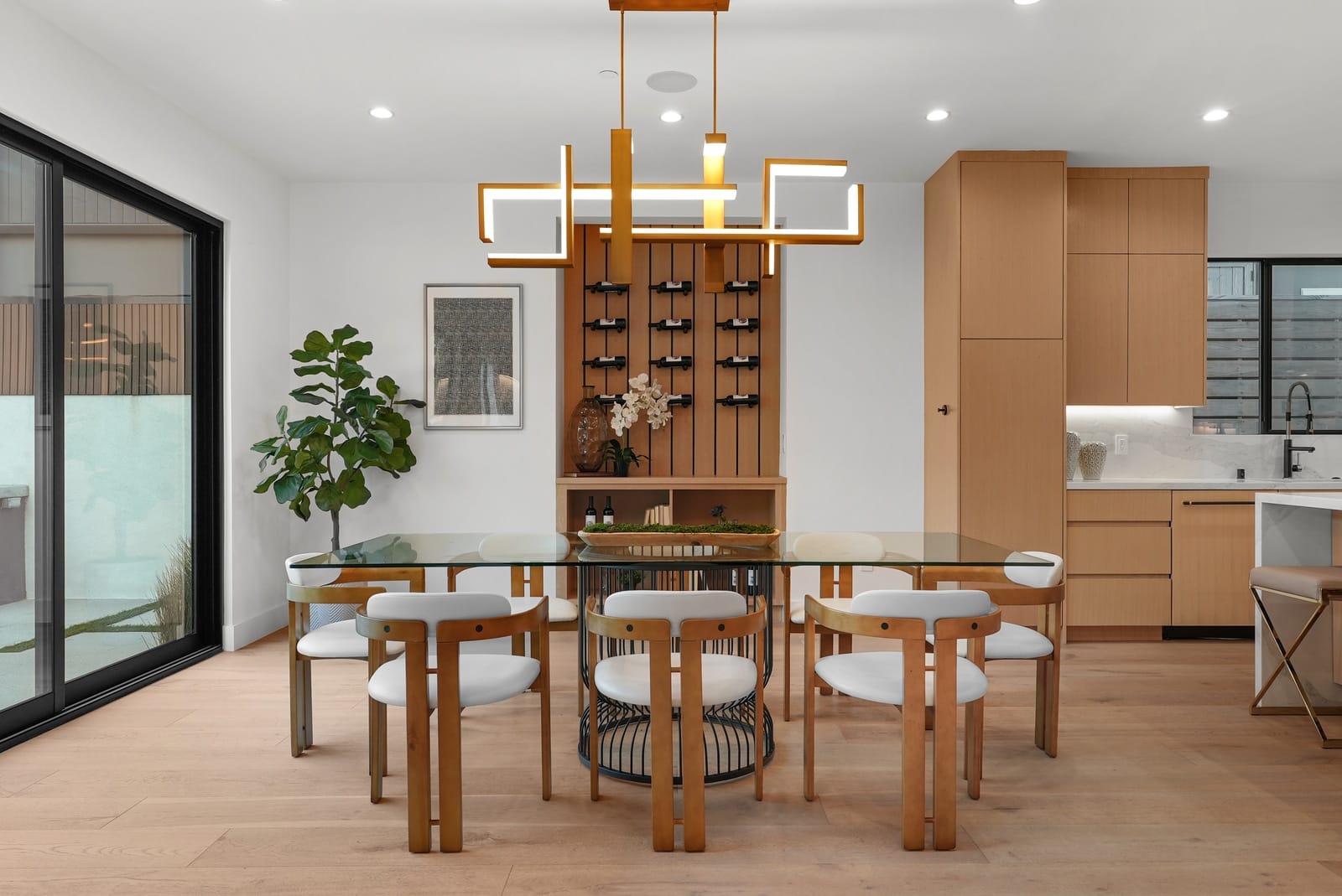 Dining table under a brass pendant, wine wall beyond