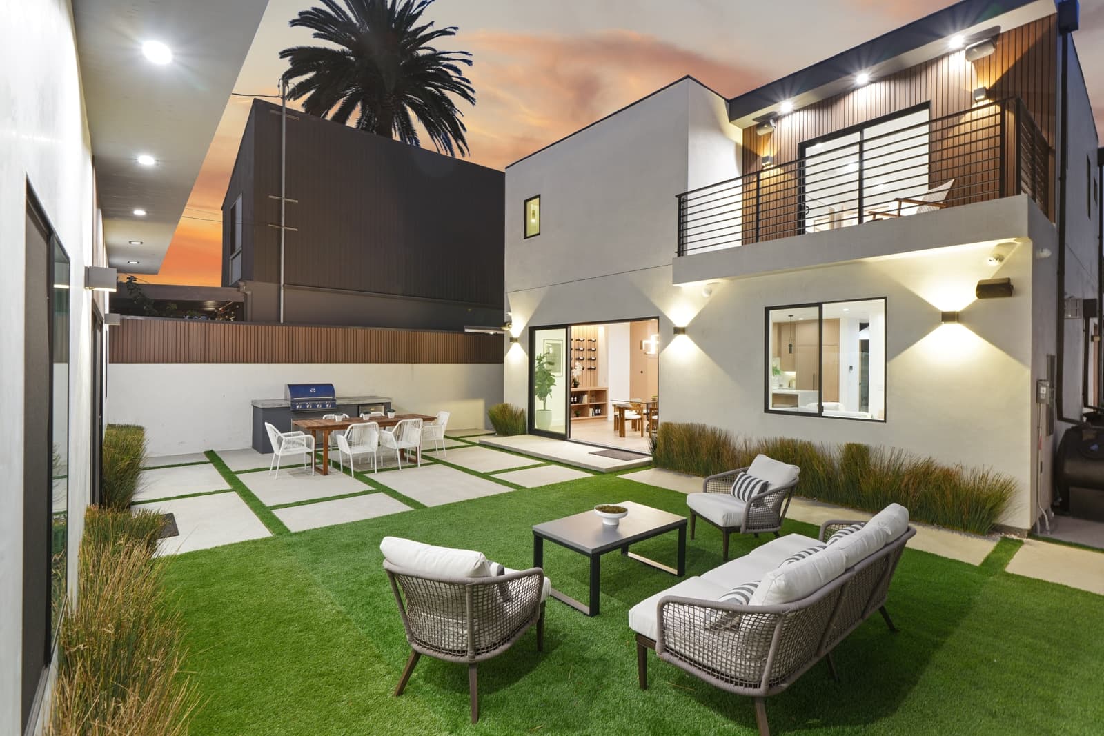 Two-storey glass and a lit yard at twilight, Mar Vista