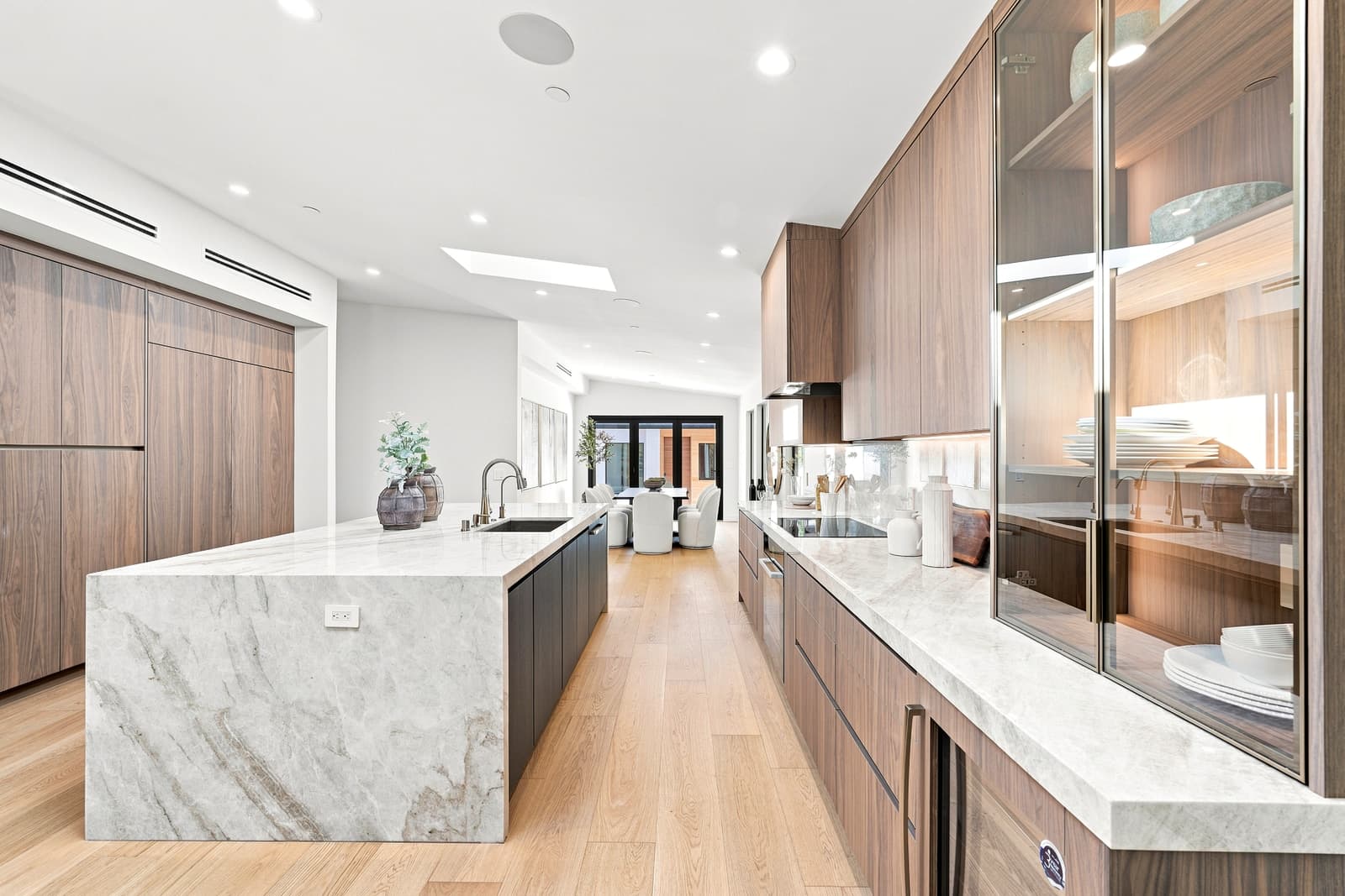 Kitchen with a marble waterfall island and walnut cabinets