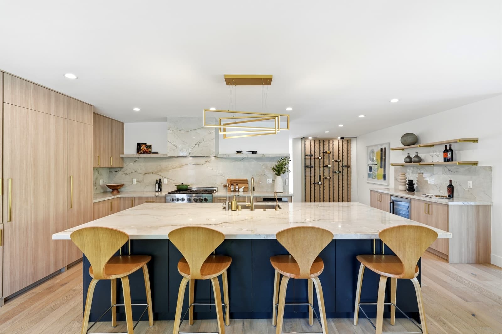Kitchen with a navy island and a brass pendant
