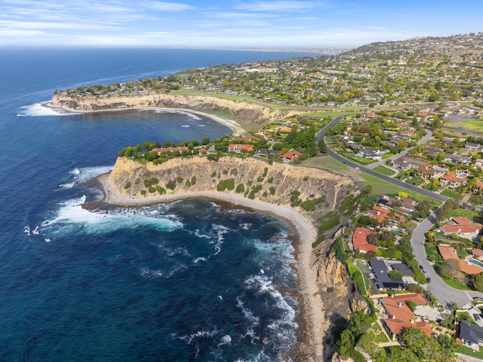 Drone view along the Palos Verdes coastline, cliffs and homes above the surf