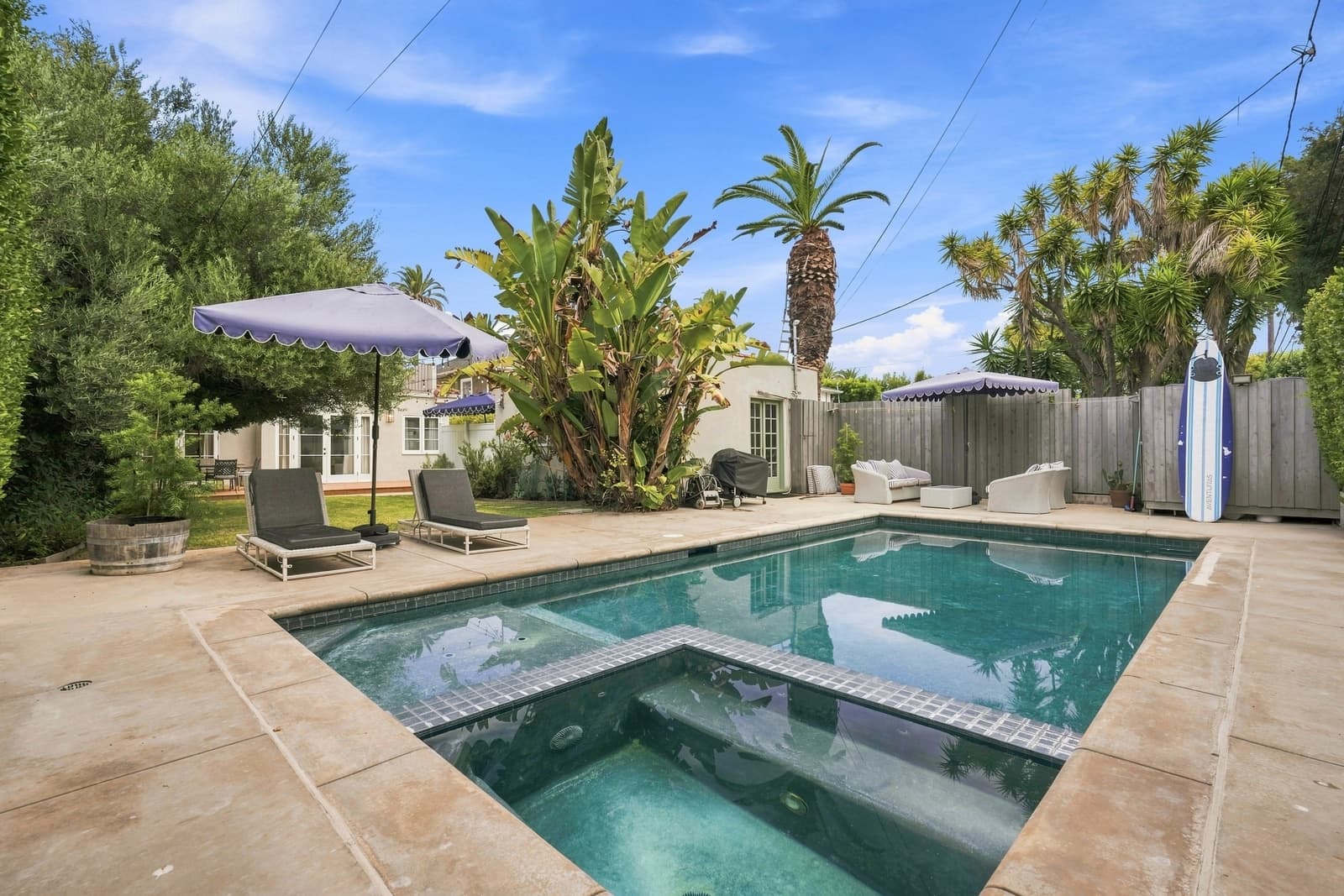 Pool and spa under palms with a blue umbrella