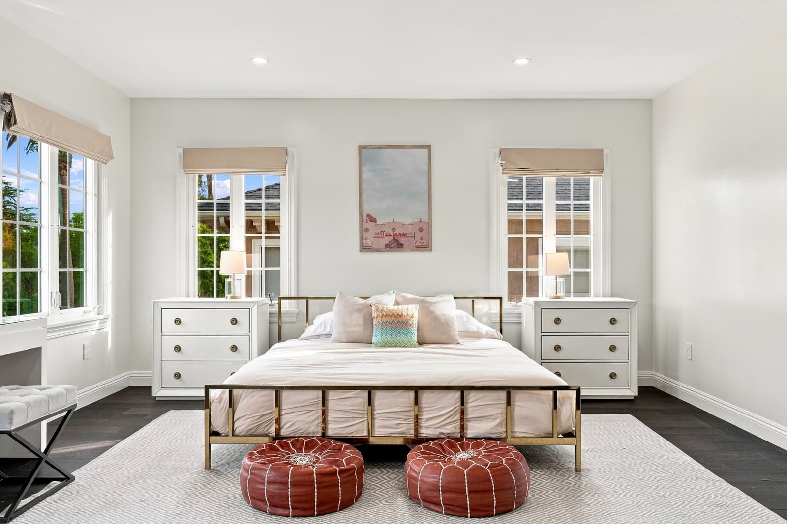 Primary bedroom with an iron bed and leather poufs