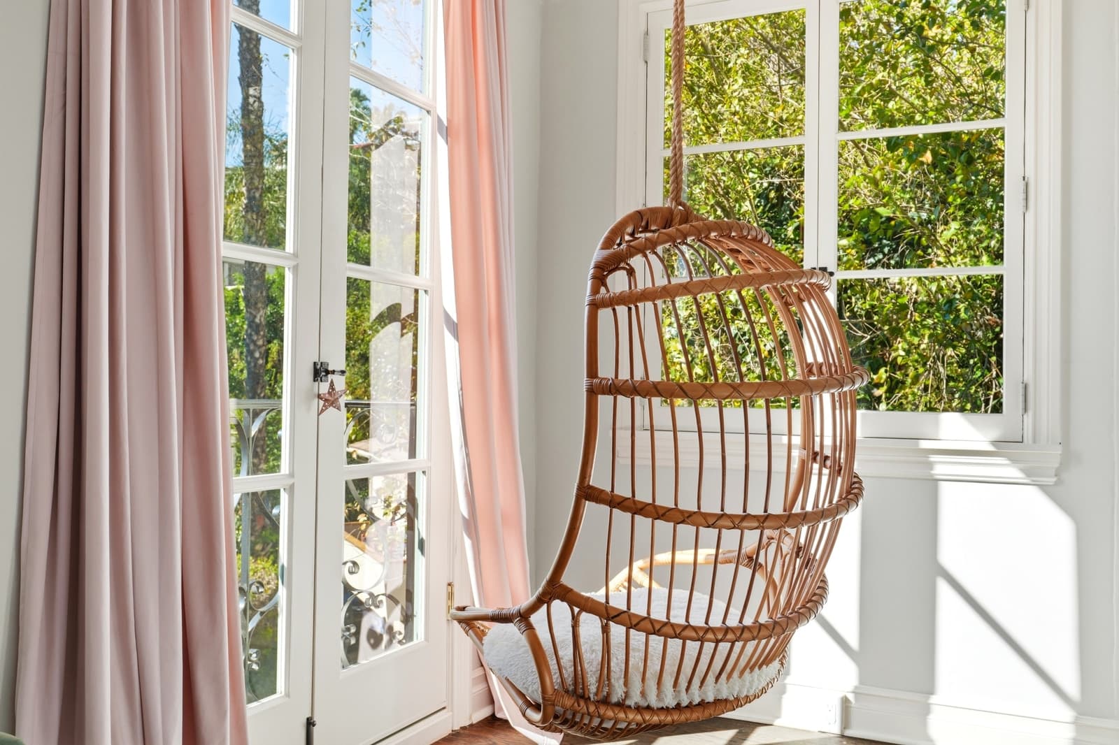 Rattan hanging chair beside French doors