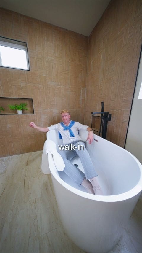 An agent lying in a freestanding tub mid-tour, from a Landon Realty Group walkthrough reel