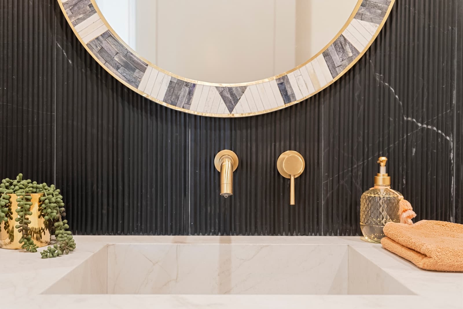 Black powder room with a round mirror and brass fixtures