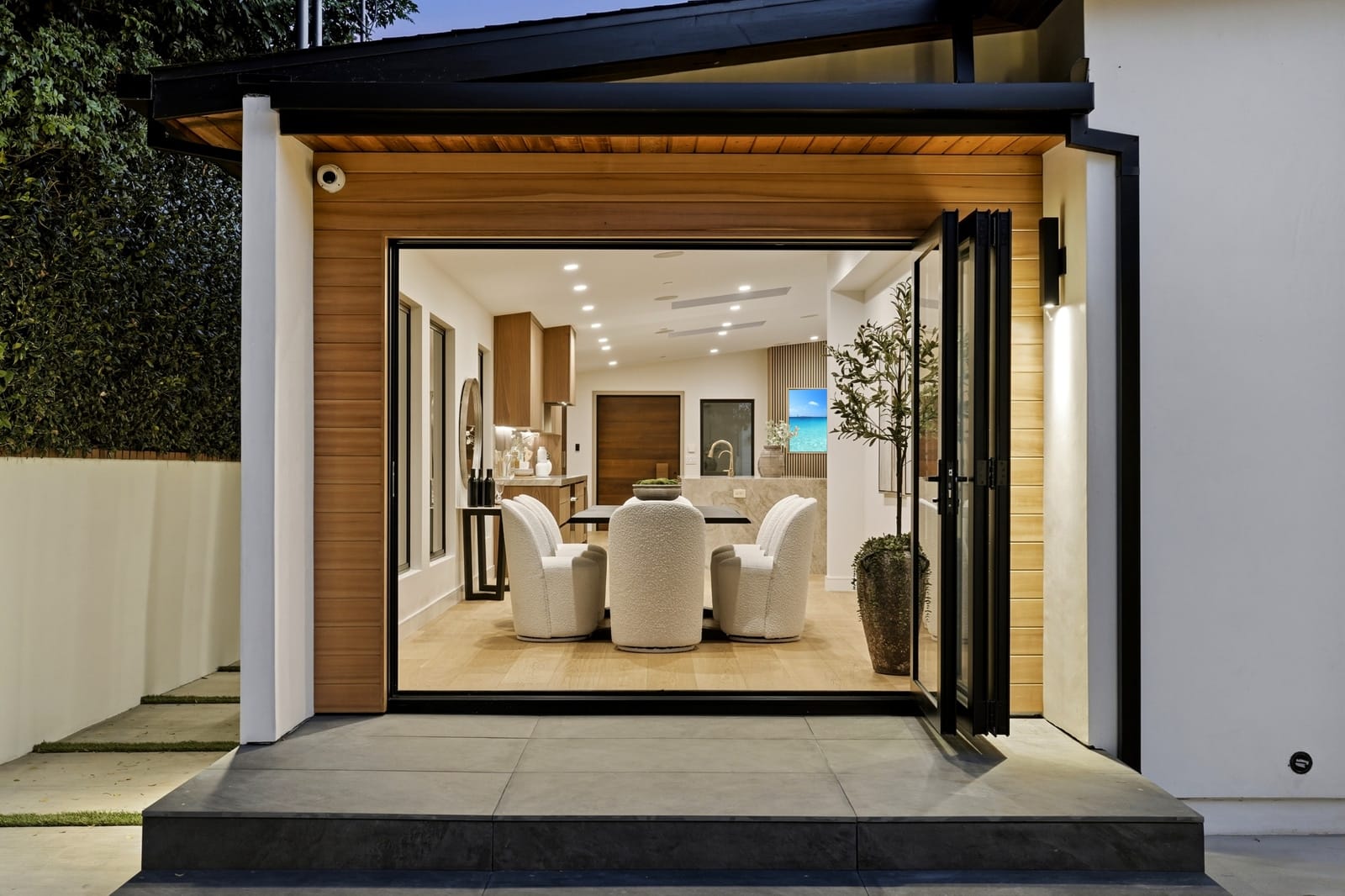 Folding glass wall open at twilight onto the dining room, seen straight on
