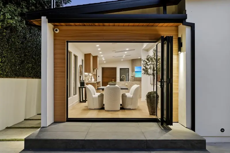 Dining room open to the patio through folding glass doors, lights on, Sherman Oaks